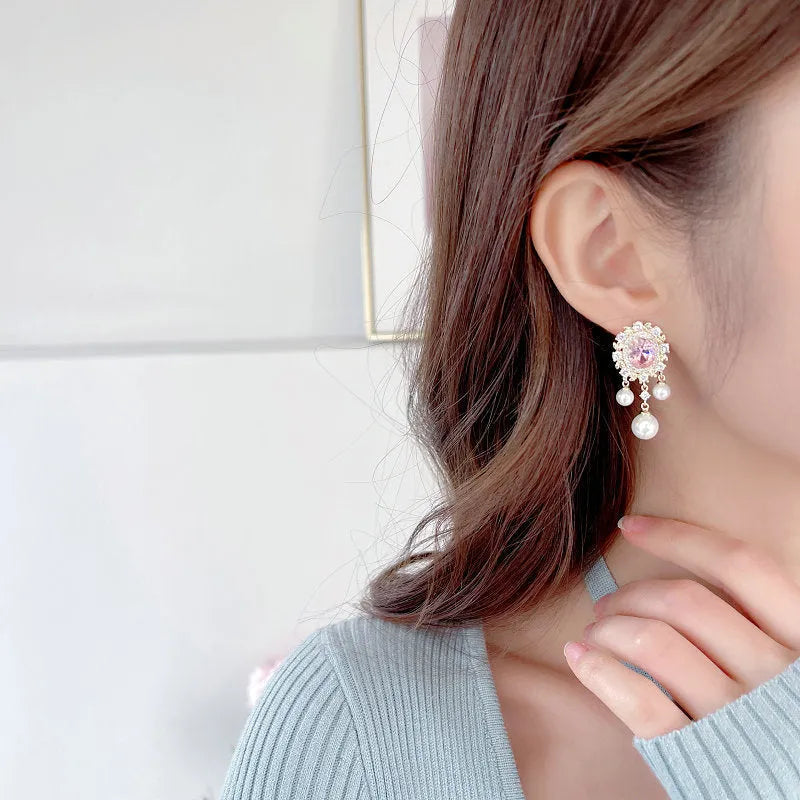 Oval-shaped copper earrings with inlaid zircon and a dangling pearl tassel in light purple.