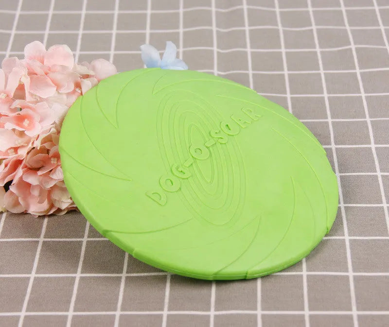 Dog training set with plastic frisbee and bite ring in orange and green colours on grass