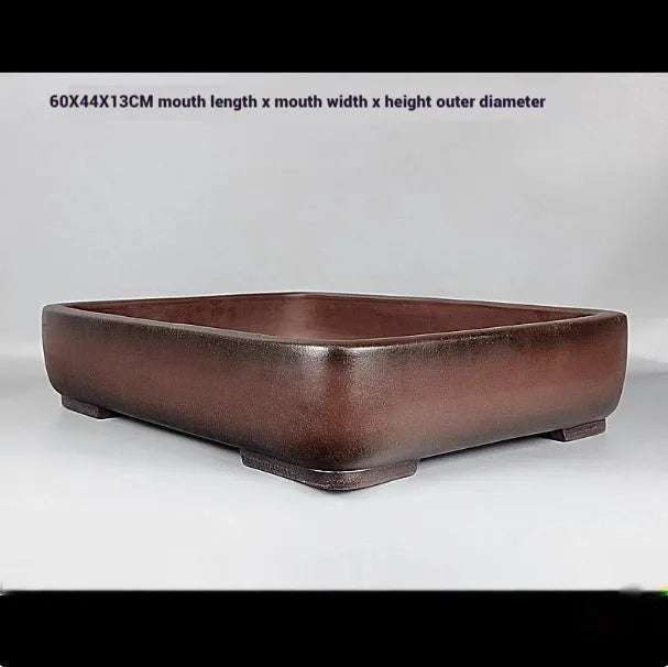 Large handmade antique rectangular purple clay flower pot on a table.