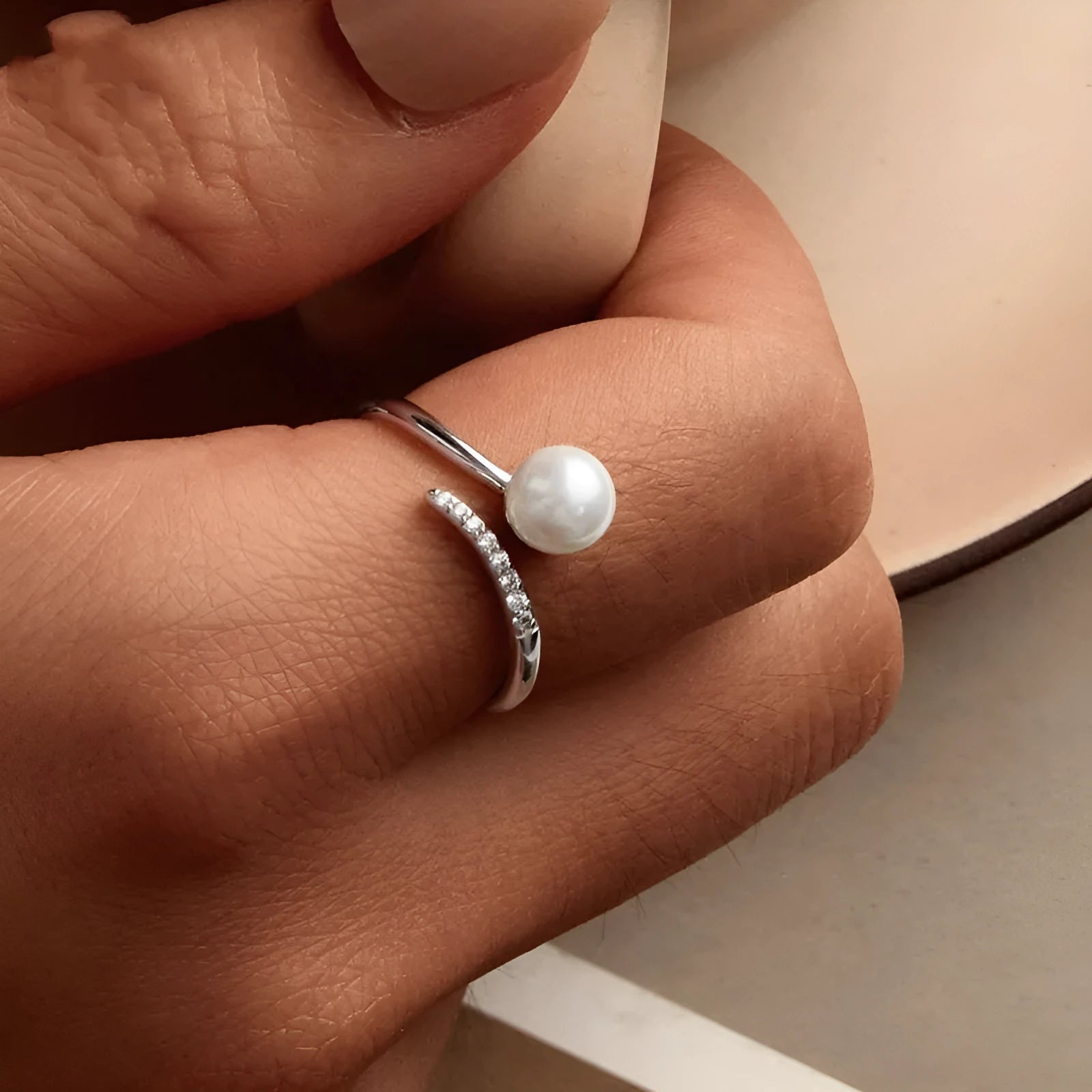 Silver adjustable ring with shell pearls showing open loop design for size adjustment