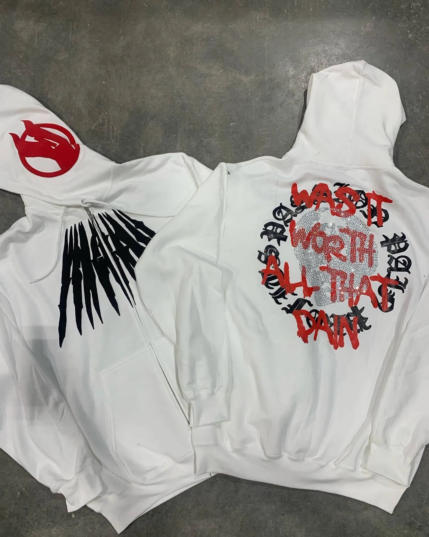 Black loose hooded sweatshirt with white skull print and rhinestone details, worn open as a cardigan.