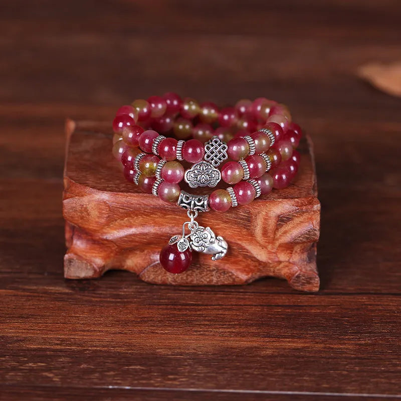 Handmade natural watermelon crystal bracelet with Chinese knots, shown in geometric national style.
