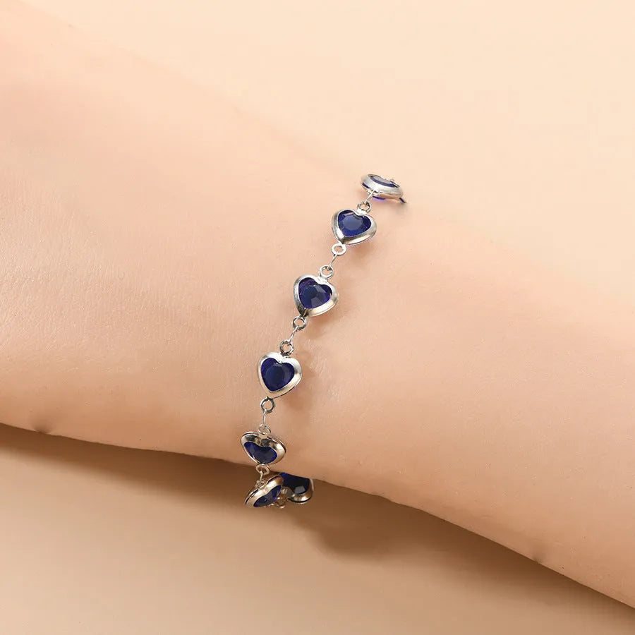 Stainless steel heart-shaped bracelet with electroplated geometric design in various colours like red, blue, and green for unisex wear.