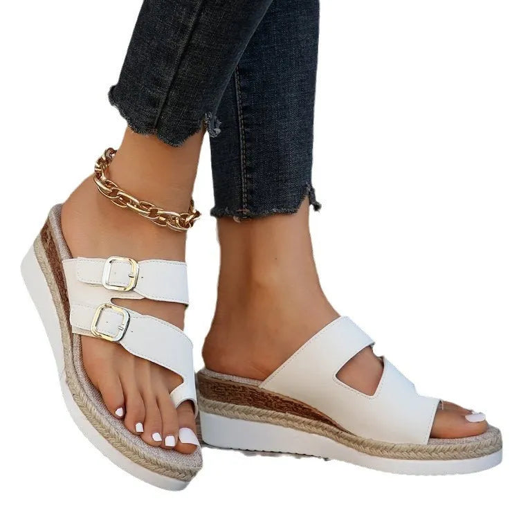 White wedge sandals with woven patent leather upper and open toe design on wooden surface