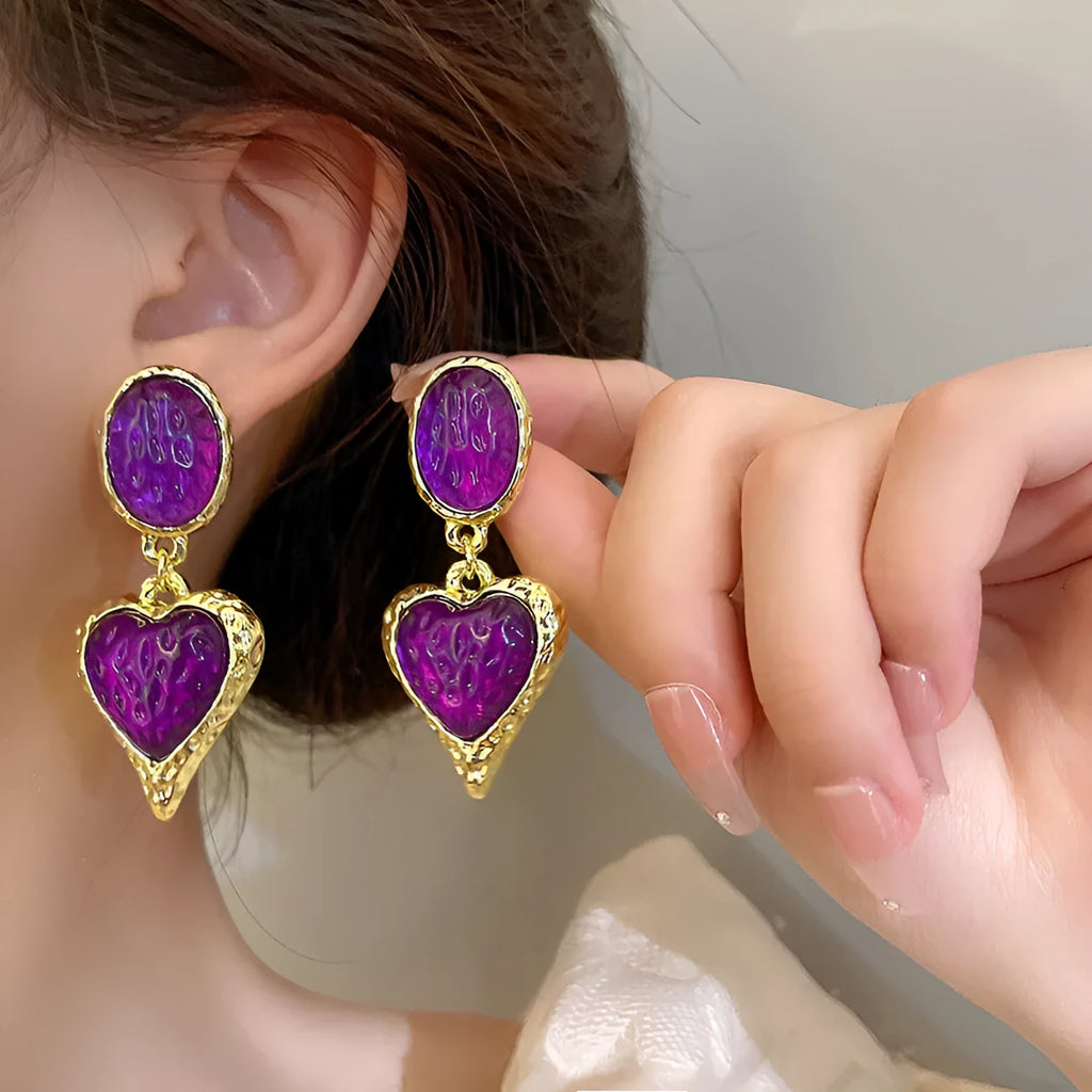 A pair of alloy pleated oval heart-shaped stud earrings with silver posts on a white background.