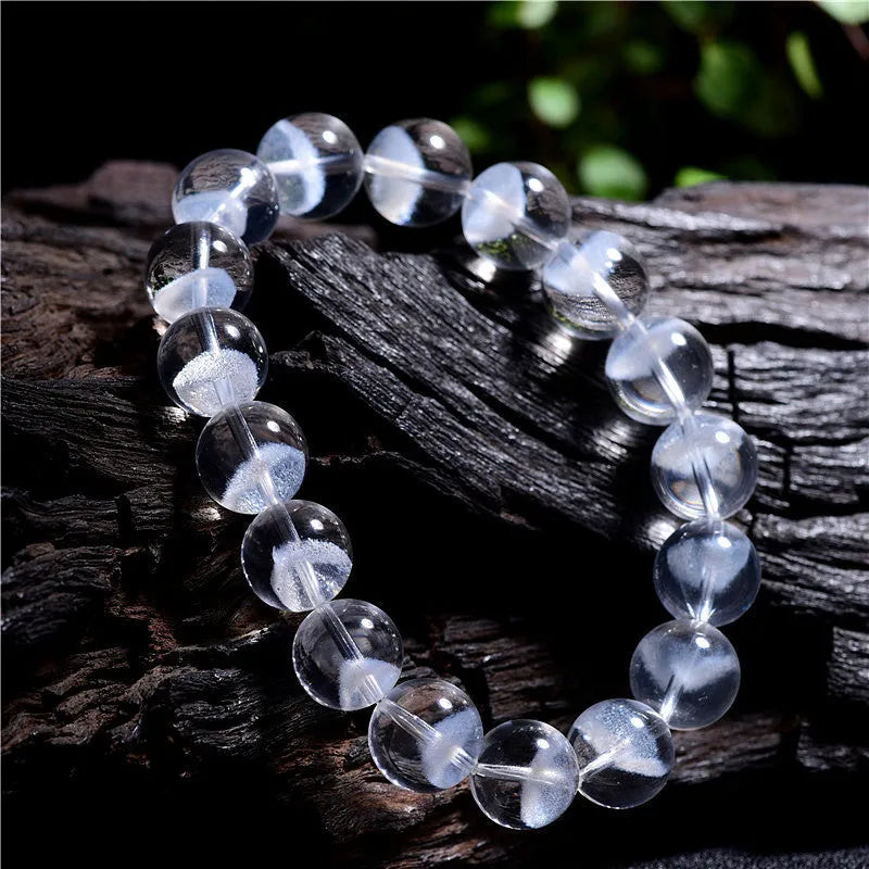 Women's white crystal pyramid bead bracelet with a silver ruyi charm on a white background.