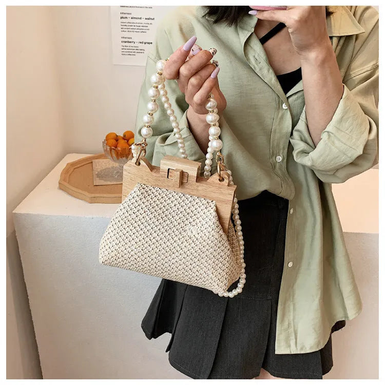 Women's straw woven shoulder bag with pearl chain detail showing interior organisation compartments