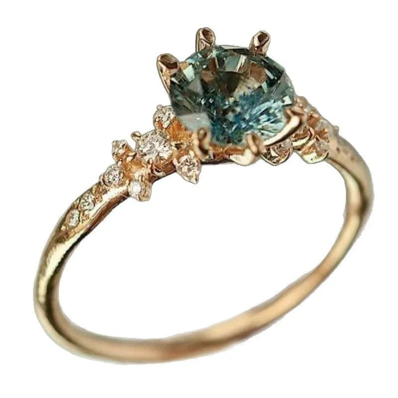Gold geometric claw setting ring with inlaid zircon stone on a band with a square pattern.