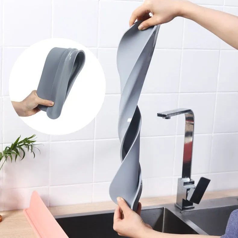 Thick grey silicone sink water blocking plate resting on a kitchen sink edge.