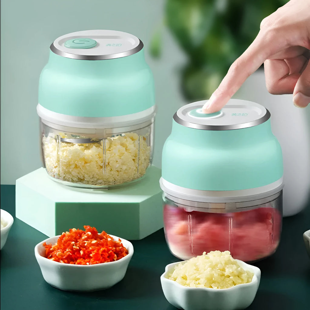Portable electric mini garlic cutter with transparent cup and stainless steel blade on kitchen counter
