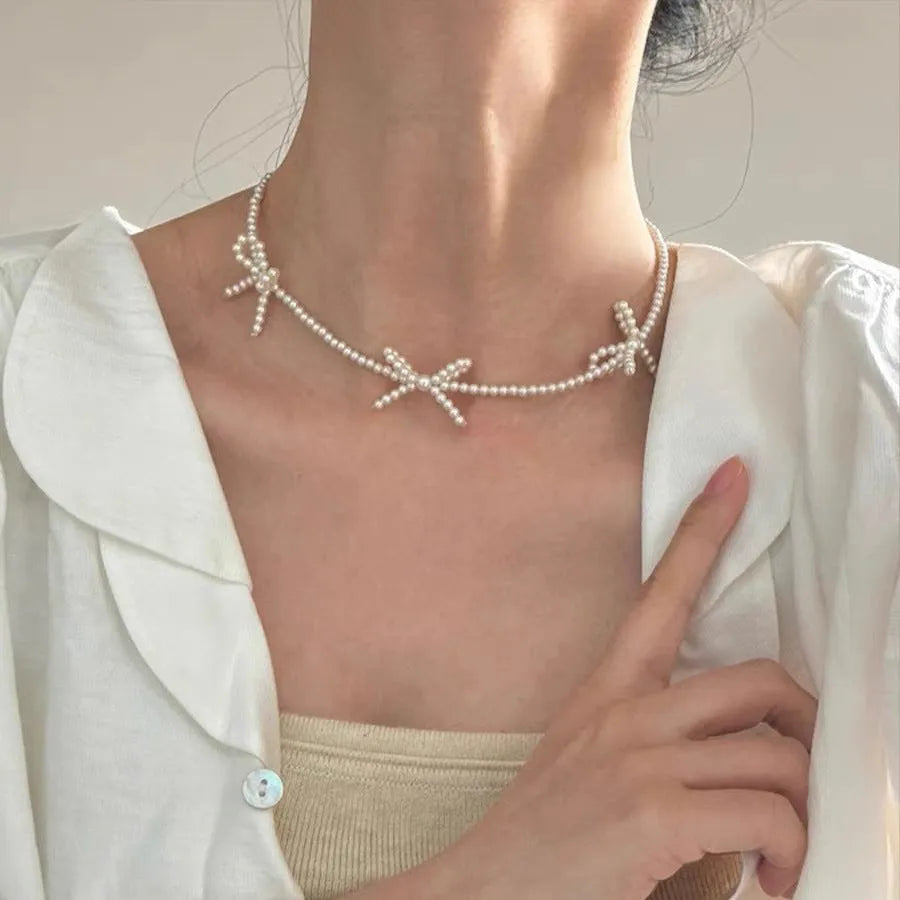 White imitation pearl necklace with geometric bow pendant on adjustable 31-40cm chain