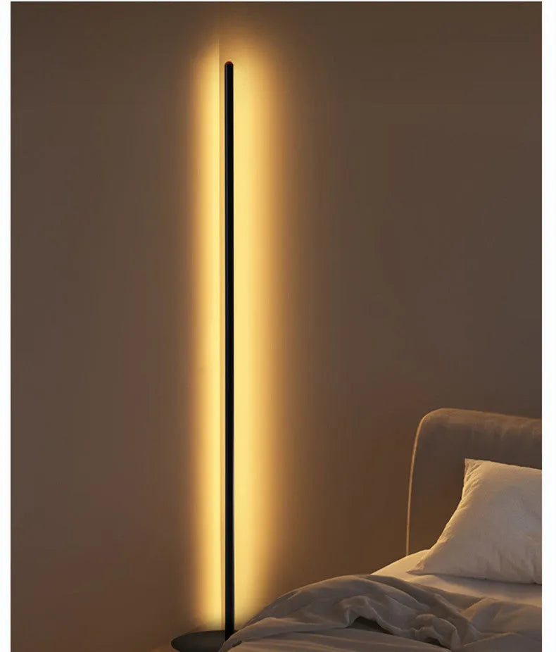Vertical aluminium alloy floor lamp with a simple modern design, shown in a living room setting.