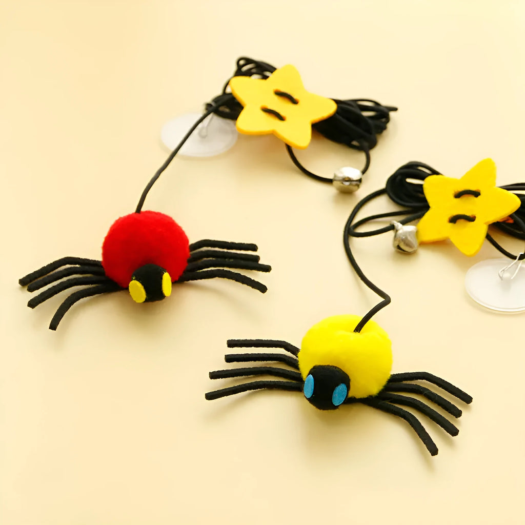 Red hanging cat toy with feather wand, bells, and spider on elastic rope, mounted on a door.